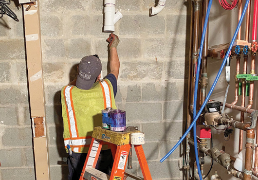 Plumbing Mechanic Victor Dutan, with Grotto Plumbing Inc., runs a new drain line for a condo renovation in Yonkers, New York.