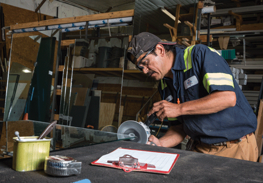 Luis Barrera fine-tunes this sheet of glass to ensure it’s exactly right for a project.