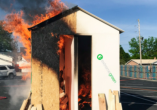 Demonstration of regular plywood vs. extremegreen, proving the latter’s superior fire ratings. (Do not try this at home.)