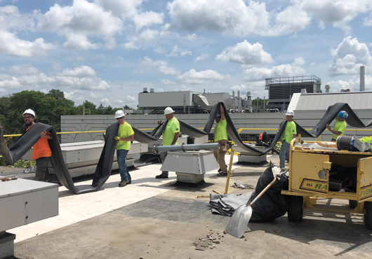 Members of Tecta America New England, LLC’s Brockton, MA, crew carry a 90-mil EPDM membrane onto the roof of the Siemens plant in Walpole, MA.