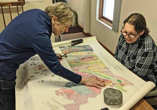 Hager GeoScience, Inc. President Jutta Hager (left) and Geologist Judy Paiva consult the Bedrock Geologic Map of Massachusetts.