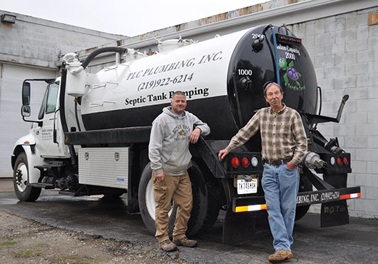 Laborer Mike Smith (left) and Technician Greg Page are pictured on a job site with a TLC Plumbing, Inc. septic truck. 