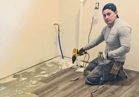 Installation of flooring, like this vinyl planking being installed in a new residence by Neighborhood Floors & More, LLC Technician Victor Garcia, is often among the last stages of a construction project. 