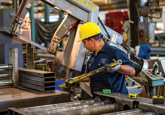 Machine Operator Julio Lazo of Central Steel Supply Company, Inc. evens off the ends of a steel bar in preparation for cutting.