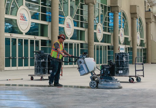 A General Coatings Corp. employee works on a waterproofing job at the San Diego Convention Center. He is grinding the concrete floor to prepare the substrate for polishing.