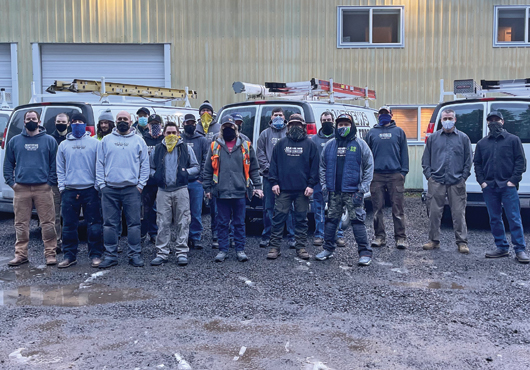 Members of Mathews Electric Corporation pose in front of the company’s office in Poulsbo, WA. 