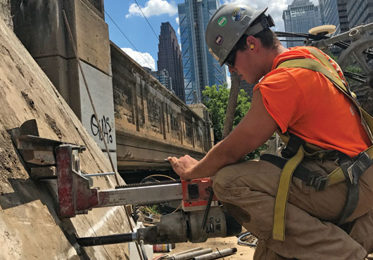 Employee T.J. Cliggett, son of owner Tommy Cliggett, performs core drilling prep work for the wire saw cutting that comes next as a part of CHESCO Coring & Cutting Inc.’s  demolition of the old Walnut Street Bridge in Philadelphia.