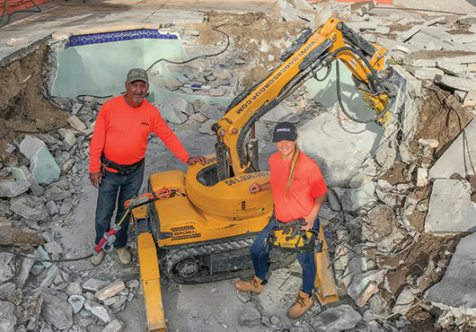 Owner Gisselle Bader, right, and her father, Alex Bader, supervise the demolition of a residential pool in West Palm Beach, Florida, using a remote-controlled robotic machine. 