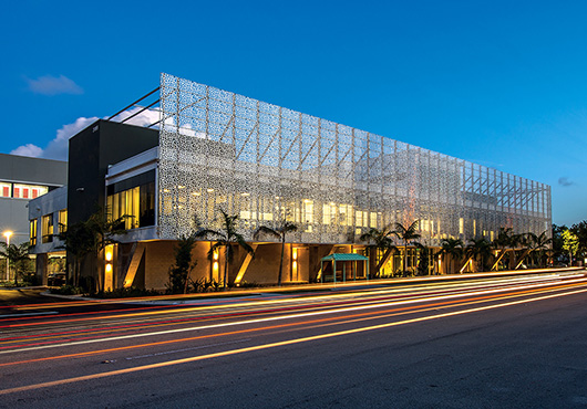 The Kaufman Lynn Construction, Inc. headquarters in Delray Beach, Florida, used unique material and finishes, including a façade featuring brushed stainless steel mesh panels that were custom designed so the pattern appears completely organic even though it repeats on the panels.