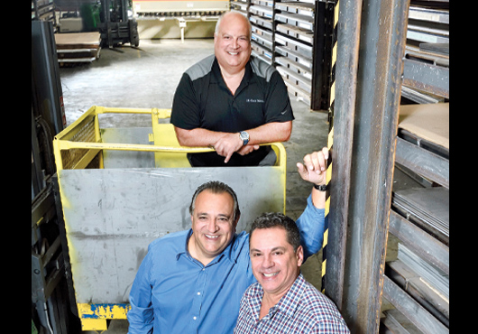 Hi-Tech Metals Inc.’s Owners Chris Doulou (left foreground), Manny Velis (rear) and Jay Valentino in front of their extensive architectural metal inventory.