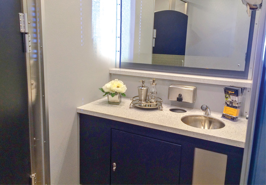Interior of a VIP luxury restroom trailer fitted with a radio and granite countertops.