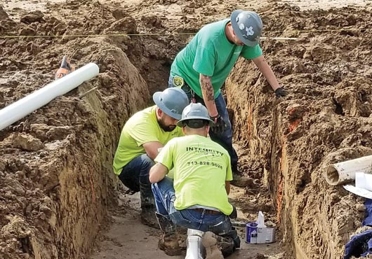 An Integrity Plumbing, LLC crew works on the installation of an underground sewer for a car dealership, Team Gillman Subaru North, in Houston.