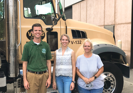 Mike Veirs Jr. (left) and Kim Veirs (middle) stand with an employee in front of the company’s new truck.