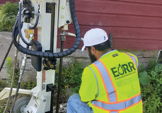 An Expert Concrete Restoration & Repair technician performs soil stabilization work on a barn to stop water from entering the structure. 