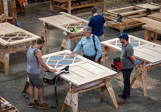 Founder and Owner Don Rees (center, light blue shirt) discusses door details with craftsmen in the RealCraft shop.