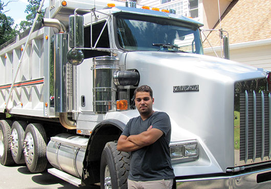 Josh George, who oversees the residential work for Paveco Asphalt Paving and Sealcoating, stands alongside the company’s new T-800 Quad-Axel dump truck.